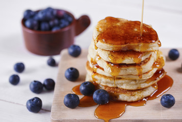 Pancakes with honey and blueberry on cutting board
