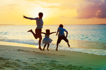 father with son and daughter have fun jump at sunset beach