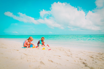 Fototapeta na wymiar little boy and girl play with sand on beach