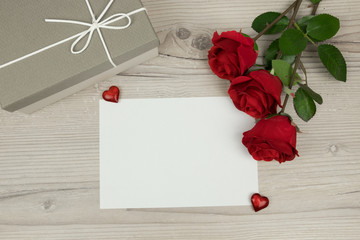 
Red roses and a blank envelope card with and a gift box on wooden background,  decoration for Valentines Day, wedding day concept, 