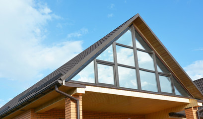 Modern house attic construction with roof guttering and panoramic mansard, attic skylight window.  Attic skylight glass wall.