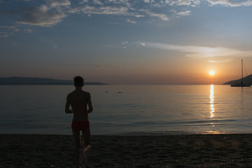 Fototapeta na wymiar Adolescent at the seashore when the sun sets
