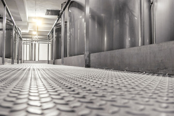 Metal floor in the factory between large metal barrels