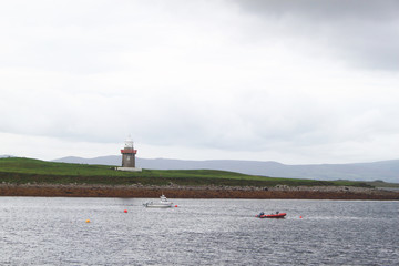 Some boats anchored at sea with a tower on land in the background