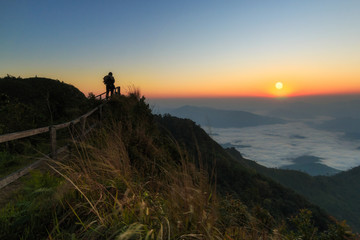 A man on the hill.Taking photos in the morning with the sun. Mountain View.High angle view at Doi Phu Chi Dao Scenic spot inWiang Kaen District, Chiang Rai,Thailand.