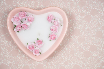 Decoration for Valentine's Day: pink heart shaped candle with little artificial flowers
