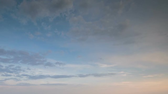 Russia, time lapse. Formation and rapid movement of white clouds of different shapes in the blue sky in late spring at sunset.