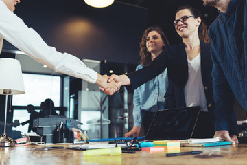 Cheerful business people shaking hands in the office. Successful partnership, meeting room...