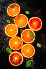 Fototapeta na wymiar Fresh raw blood oranges, halves, with mint, on dark rusty background copy space top view