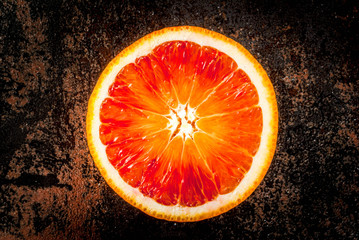Fresh raw blood oranges, half, with mint, on dark rusty background copy space top view