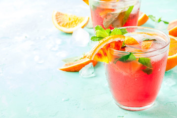 Summer cold drink, blood orange mint cocktail - mimosa, mojito or sangria,  light blue background, copy space