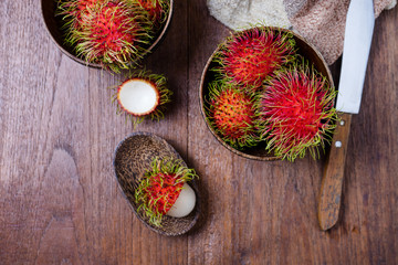 Fresh rambutans in a woodean bowl on wooden background.