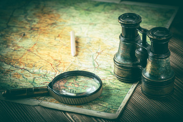 Magnifying glass and binoculars on the old map.