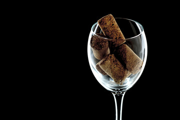 a glass of wine with plugs inside close-up. the glass is on a black background (isolate).