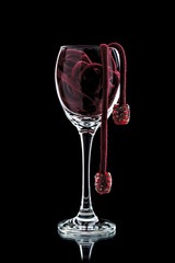 a glass of wine with red beads (decoration) inside close-up on a black background (isolate).