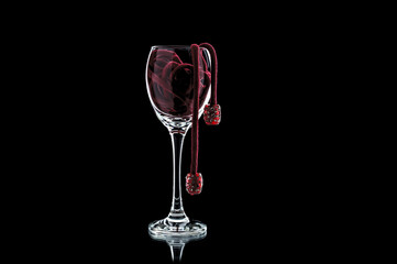a glass of wine with red beads (decoration) inside close-up on a black background (isolate).
