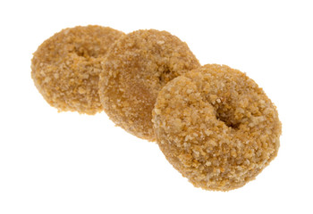 Three small bite size caramel flake donuts in a row isolated on a white background.