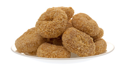 Side view of several small bite size caramel flake donuts on a plate isolated on a white background.