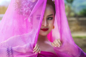 Beautiful Thai woman wearing traditional Thai dress with silk fabric cover her head