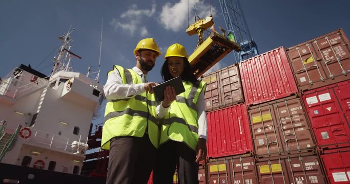Businessman and dock worker shake hands at a busy shipyard. Shot on RED Epic.
