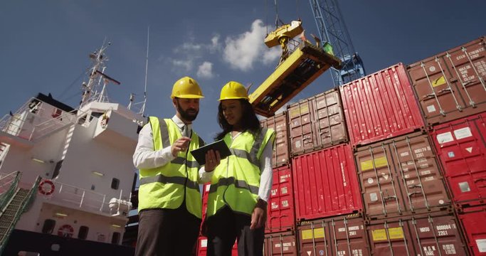 Businessman and dock worker shake hands at a busy shipyard. Shot on RED Epic.