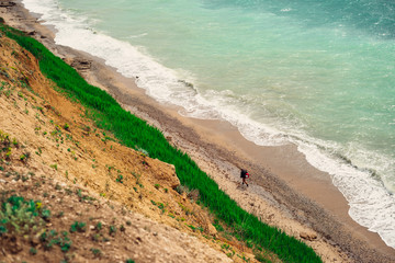 against the background of a bluff of the blue sea and along the shore there is a man