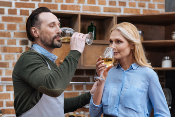 husband and wife drinking wine from glasses in kitchen
