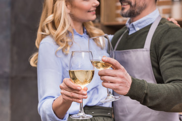 cropped image of husband and wife clinking with glasses of wine