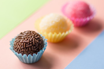 Brigadeiro Beijinho and Bicho de Pe: sweets from Brazil. Child birthday party. Candy balls in straight line. Colorful background.