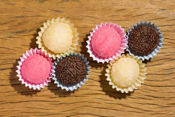 Brigadeiro Beijinho and Bicho de Pe: sweets from Brazil. Child birthday party. Overhead of candy ball on rustic wood table.