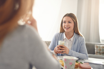 Hübsche junge Frau trinkt einen Cafe Latte beim Frühstück