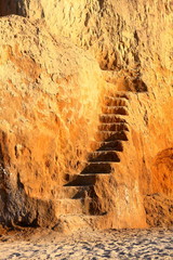 A steep climb up srairs carved in cliff of loamy soil. Staircase, carved in clay crag