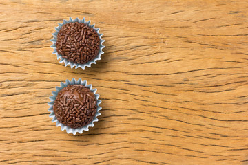 Brigadeiro is a chocolate truffle from Brazil. Cocoa and sprinkles of chocolate. Children birthday party sweet. Overhead of candy ball on rustic wood table.