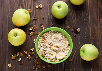 oatmeal with fruit and dried fruits.bananas,apples.wooden table.healthy organic food concept.top view