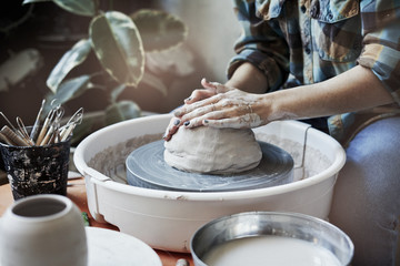 Ceramic studio, craft working process with clay potter's wheel, close-up of hands doing a pot or a vase, object