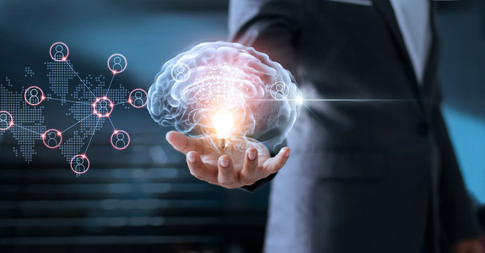  Businessman holding virtual brain and light bulb with global networking connection, brainstorm and business concept