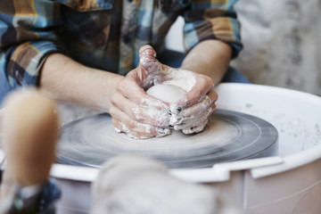 Ceramic studio, craft working process with clay potter's wheel, close-up of woman hands doing object