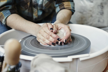 Ceramic studio, craft working process with clay potter's wheel, close-up of woman hands doing object