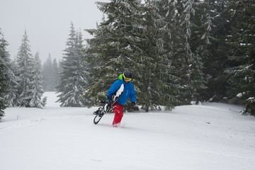 Adventurer with a snowboard in his hands rises up the mountain slope