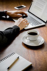 Man at desk working on laptop computer with coffee