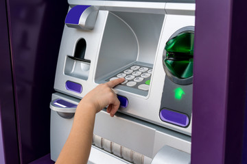 Hand of Asian woman pressing digit buttons on ATM machine.