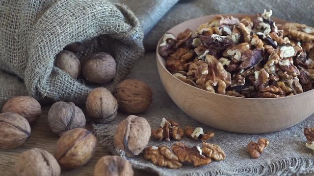 Walnut kernels on rustic wooden table. Dark and moody style.