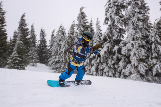 Snowboarder rides downhill, turns along mountain slope