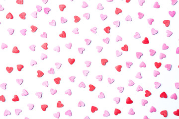 Red and pink sugar hearts on white forming a cute background for St.Valentine’s Day.