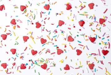Red sugar hearts and multicolored sugar roads forming a cute background for St. Valentine’s Day.
