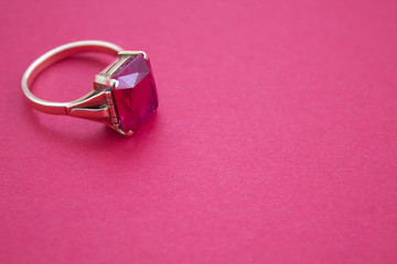 gold jewelry handmade with ruby on red background closeup