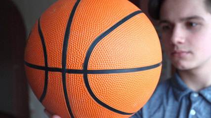 Fototapeta premium A handsome boy (teenager) is holding a basketball, a brunette with long hair.