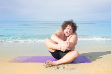 Fitness at the sea. Funny fat guy and yoga. 