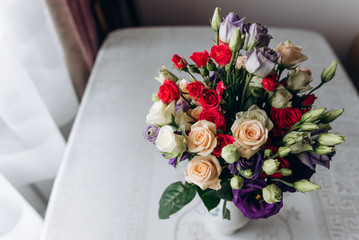 Bouquet of red, pink, white and violet roses standing on the table in a vase