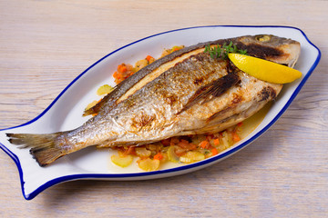 Grilled seabream on carrot, onion and celery stalks